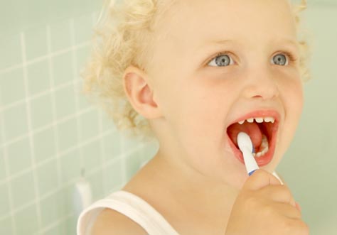 [Translate to Polski:] kid cleaning teeth